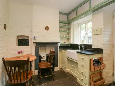 a kitchen with a table and a fireplace at Teacher's Cottage in Presteigne