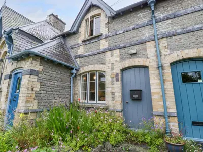 a stone house with blue doors and flowers at Teacher's Cottage in Presteigne