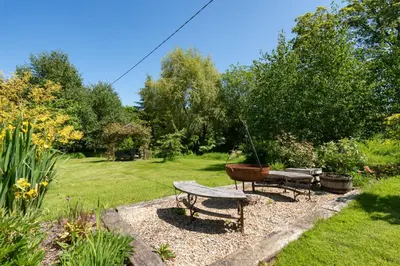 a garden with a bench and a bowl on a table at The Barn at Middle Farm and Cottages in Picklescott
