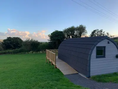 a small shed with a wooden ramp in a field at Dysynni Pod in Tywyn