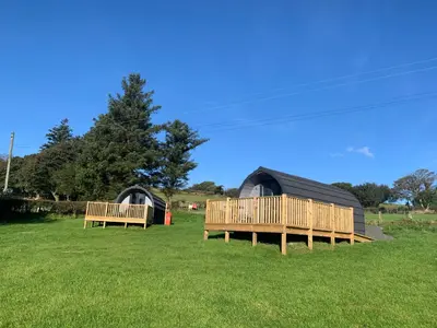 two wooden benches sitting in a grass field at Dysynni Pod in Tywyn