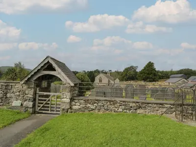an old stone house with a gate and a stone fence at Dysynni Pod in Tywyn