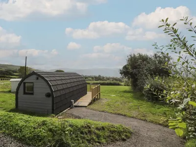 a small shed with a wooden ramp in a field at Tarrenhendre Pod in Tywyn