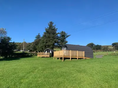 a cabin with two decks on a grass field at Tarrenhendre Pod in Tywyn