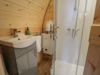 a bathroom with a sink and a shower at Tarrenhendre Pod in Tywyn