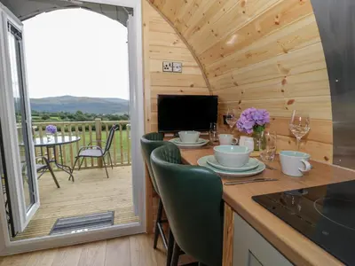 a dining room with a table and a balcony at Tarrenhendre Pod in Tywyn