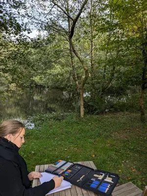a woman sitting on a picnic table with a book at Go Eco Glamping in Lampeter