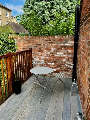 a table and two chairs on a wooden deck at Flower Cottage by Ludlow Castle with Onsite Parking in Ludlow