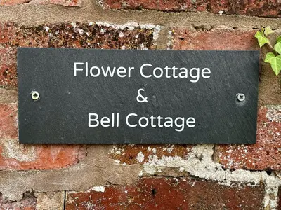 a sign on a brick wall with the words flower cottage and bell cottage at Flower Cottage by Ludlow Castle with Onsite Parking in Ludlow