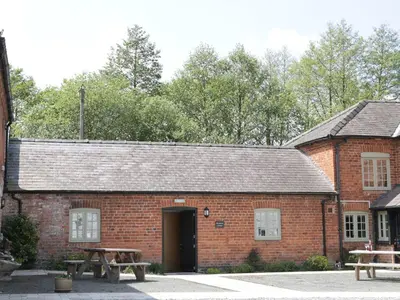 a brick building with a table and benches in front at Woodside Cottage in Newtown