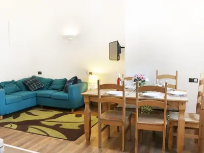 a living room with a table and a blue couch at Woodside Cottage in Newtown