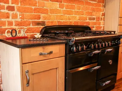 a black stove in a kitchen with a brick wall at Garden Cottage in Newtown