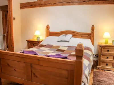 a bedroom with a wooden bed and two night stands at Garden Cottage in Newtown