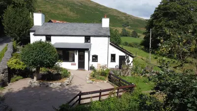 a white house with a fence in front of it at Maengwynedd, Llanrhaeadr Ym Mochnant in Oswestry
