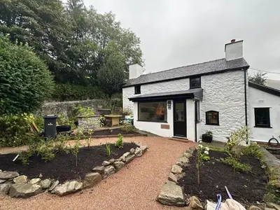 a small white building with a garden in front of it at Maengwynedd, Llanrhaeadr Ym Mochnant in Oswestry