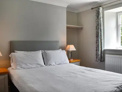a bedroom with a bed with white sheets and a window at Pengarreg Fawr- Uk47774 in Llanilar