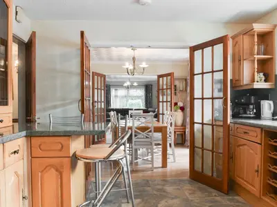 a kitchen with wooden cabinets and a dining room at Tan Y Gaer in Aberystwyth