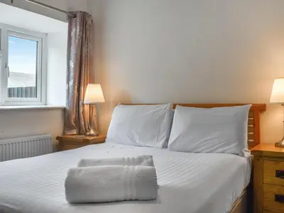 a bedroom with a bed with white sheets and a window at Cottage 1- Uk47770 in Llanilar