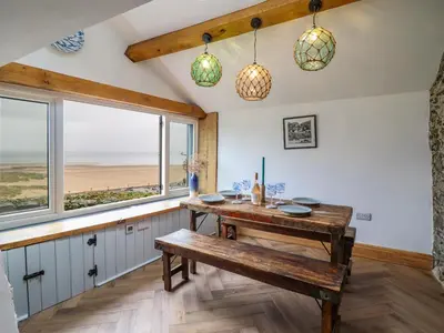 a dining room with a bench and views of the ocean at Pengarreg in Barmouth