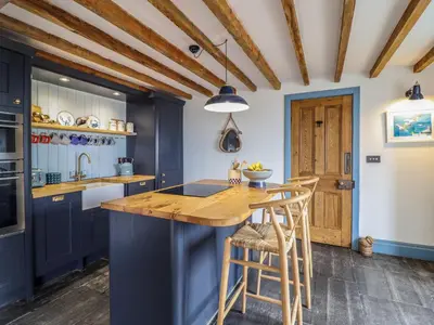 a kitchen with blue cabinets and a wooden island with stools at Pengarreg in Barmouth