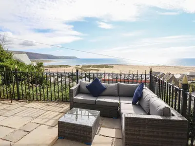 a patio with a couch and a view of the beach at Tonnau Yr Oleu or Waves of Light in Barmouth