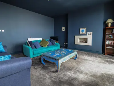 a blue living room with a couch and a coffee table at Tonnau Yr Oleu or Waves of Light in Barmouth