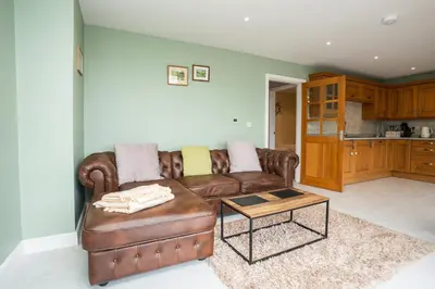 a living room with a brown leather couch and a table at Carreg Wen in Harlech
