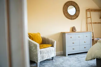 a bedroom with a chair and a dresser and a mirror at Carreg Wen in Harlech