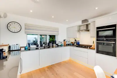 a kitchen with white cabinets and a clock on the wall at 5 Bed in Aberdovey oc-t29402 in Aberdyfi