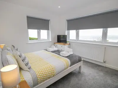 a bedroom with a bed with two windows and a television at Melin Y Plas in Barmouth