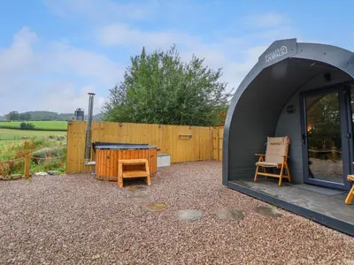 a tent with a table and chairs in a yard at Heron Pod in Oswestry