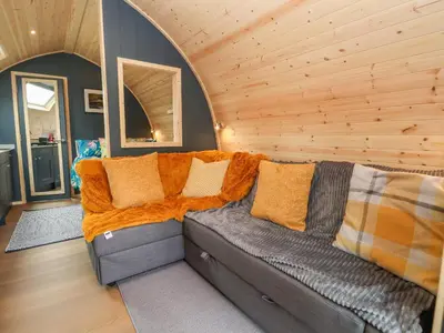 a living room with a couch in a wooden room at Heron Pod in Oswestry