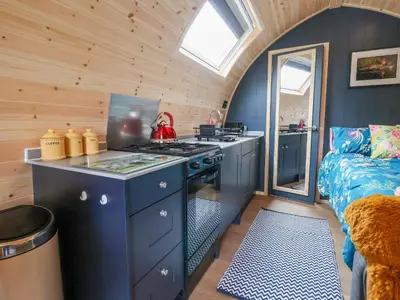 a kitchen with a stove and a bed in a room at Heron Pod in Oswestry