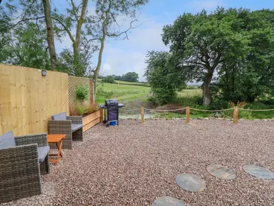 a gravel patio with benches and a fence at Heron Pod in Oswestry