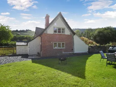 a small house with a grassy yard in front of it at Ty-Ucha Cottage in Llangollen