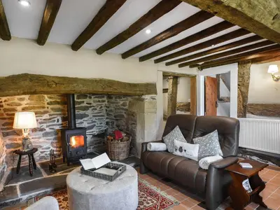 a living room with a leather couch and a stone fireplace at Ty-Ucha Cottage in Llangollen
