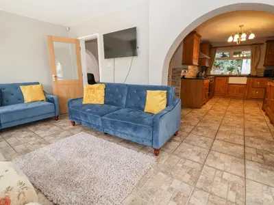 a living room with two blue couches and a kitchen at The Willows in Llangollen