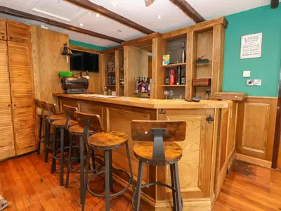 a bar with wooden cabinets and stools in a room at The Willows in Llangollen