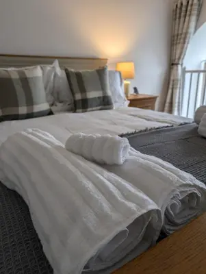 a bed with white sheets and pillows on it at 2 Chapel Nazareth in Penrhyndeudreath