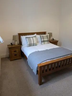 a bedroom with a large bed and two night stands at 2 Chapel Nazareth in Penrhyndeudreath
