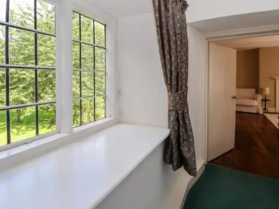 an empty room with two windows and a green rug at New Hall in Wrexham