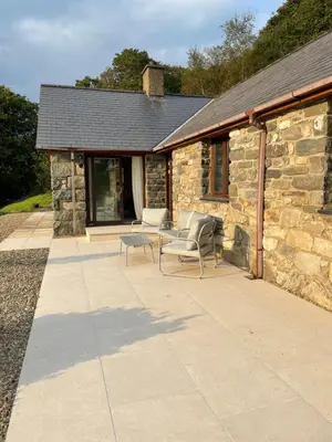 a stone house with two chairs and a table on a patio at Llety Cynnes in Machynlleth