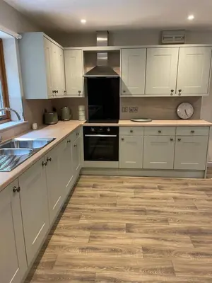 a kitchen with white cabinets and a wooden floor at Llety Cynnes in Machynlleth
