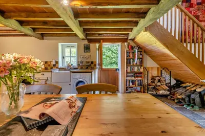 a dining room with a wooden table and a kitchen at 1 Bed in Llwynygroes oc-y29714 in Llangeitho
