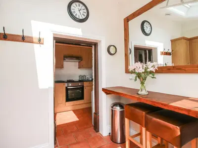 a kitchen with a counter and a clock on the wall at Moorhen Cottage in Ludlow