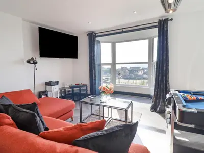 a living room with orange furniture and a large window at Gwynfa in Barmouth