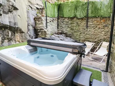 a hot tub in a backyard with a stone wall at Gwynfa in Barmouth