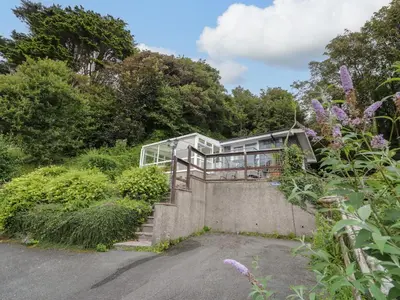 a house on the side of a hill with trees at Woodland Roost in Barmouth