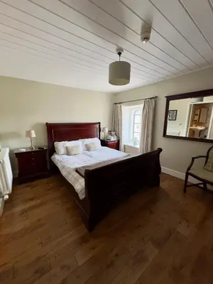 a bedroom with a large bed and a mirror at Cross Hands Hotel in Llanybydder