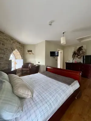 a bedroom with a bed and a living room at Cross Hands Hotel in Llanybydder